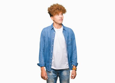 Afro saçlı görünümlü yan ve dik dik bakma uzağa düşünce gülümseyen denim ceket giyen genç yakışıklı adam.