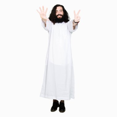 Gösterilen ve parmakları ile işaret İsa Mesih giyinen adam kendinden emin ve mutlu gülümseyerek süre yedi numara.