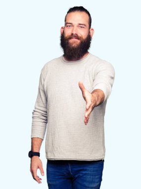 Genç Sarışın giyen sıradan kazak tebrik ve konuksever dost sunan karşılıklı gülümseyen adam. Başarılı iş.