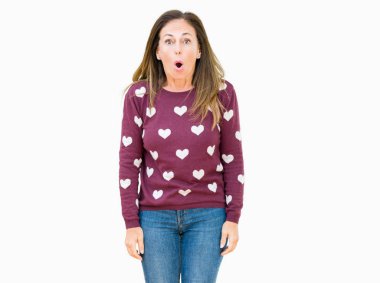 Güzel orta yaş kadın giyiyor kalpler kazak korkuyor ve şok sürpriz ifade ile izole arka plan üzerinde korku ve yüz heyecanlı.