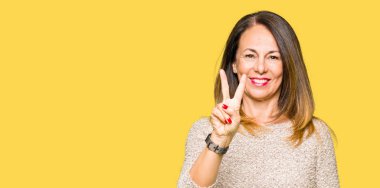 Gösterilen ve parmakları ile işaret güzel orta yaş kadın giyiyor moda kazak ikincisi ise kendinden emin ve mutlu gülümseyerek.