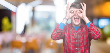 Dilini, parmaklarının arasından baktığını yapışmasını dürbün gibi ok jest yapıyor izole arka plan üzerinde gözlük takan yakışıklı delikanlı. Deli ifade.