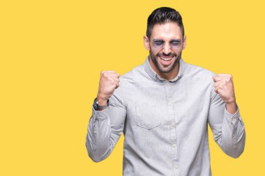 Yakışıklı delikanlı üzerinde güneş gözlüğü takıyor arka plan çok mutlu ve heyecanlı kaldırdı, silah ile kazanan jest yapıyor gülümseyen ve başarı için çığlık izole. Kutlama kavramı.