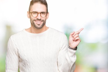 Kameraya bakarak yan el ve parmak ile işaret yüzünde kocaman bir gülümseme ile izole arka plan üzerinde gözlük takan genç yakışıklı adam.