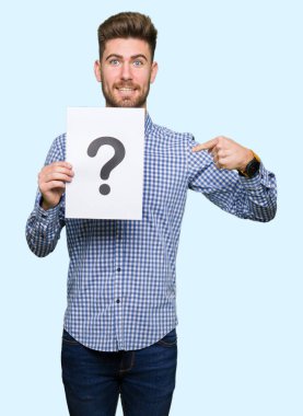 Genç yakışıklı sürpriz yüz işaret parmağı kendisine soru işareti ile holding Kağıt adam