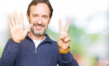 Gösterilen ve parmakları ile işaret kazak giyen orta yaş yakışıklı adam kendinden emin ve mutlu gülümseyerek süre yedi numara.