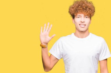 Gösterilen ve parmakları ile işaret casual beyaz t-shirt giyen afro saçlı genç yakışıklı adam kendinden emin ve mutlu gülümseyerek süre beş numara.