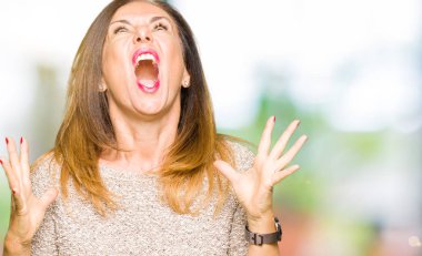 Güzel orta yaş kadın moda kazak deli ve deli çığlık giyiyor ve agresif ifade ve silah ile bağırdı kaldırdı. Hayal kırıklığı kavramı.