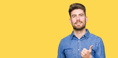 Hareketi el ile mutlu yaşasın yaparken rahat kot gömlek giymiş genç yakışıklı sarışın adam. Başarı gösteren kameraya bakarak ifade onaylama.