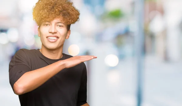 Tânăr Chipeș Păr Afro Purtând Tricou Negru Gestând Mâinile Arătând — Fotografie, imagine de stoc