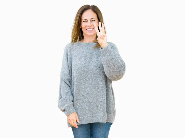 上冬のセーターを着て美しい中年女性分離を示す背景と自信を持って 幸せな笑みを浮かべて 指で上向きナンバースリー — ストック写真