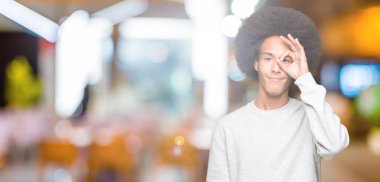Afro saç ile genç Afrikalı Amerikalı adam, el gülümseyen ok jest yapıyor sportif sweatshirt giyen, göz mutlu yüz ile parmaklarla bakıyor.