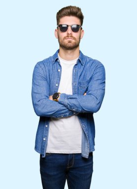 Denim ceket şüpheci ve sinir, onaylamayan ifade yüz çapraz kolları üzerinde giyen genç yakışıklı zarif adam. Negatif kişi.