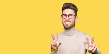 Zafer işareti yapıyor parmak gösterilen kamera seyir gülümseyen genç yakışıklı iş adam gözlük takıyorsun. İki numaralı.