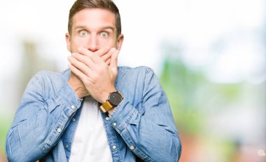 Mavi gözlü ve sakallı kot ceket giyen yakışıklı adam hata için elleri ile ağız örtülü şok. Gizli kavram.