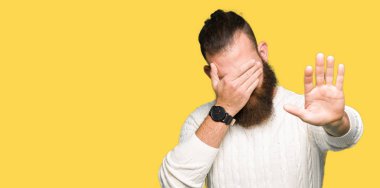 Kış kazak kapsayan giyen genç hipster adam gözleri ile el ve stop jest ile acı ve korku ifadesi. Utandım ve negatif kavramı.