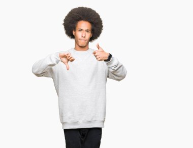 Afrikalı-Amerikalı genç afro saçlı sportif kazak yapıyorsun başparmak yukarı ve aşağı giyiyor, anlaşmazlık ve anlaşma ifade. Deli çatışma