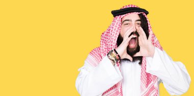 Geleneksel keffiyeh eşarp ağzına sesle elleriyle kızgın bağırarak giymiş uzun saçlı Arap iş adamı