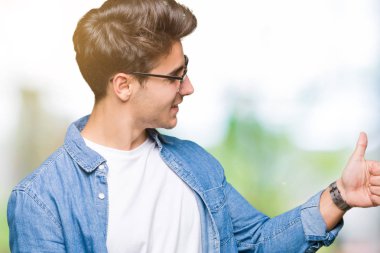 Yanına bir jest yapıyorsun gülümseyen izole arka plan gurur, seyir üzerinde güneş gözlüğü takıyor yakışıklı delikanlı yaşasın