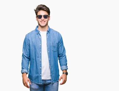 Genç yakışıklı adam yüzünde mutlu ve güzel bir gülümseme ile izole arka plan üzerinde güneş gözlüğü takıyor. Şanslı kişi.