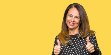 Moda ceket onaylama giyen güzel orta yaş kadın el ile pozitif jest yapıyor gülümseyen ve başarı için mutlu yaşasın. Kamera, kazanan jest arıyorsunuz.