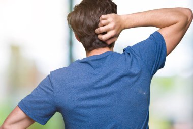 İzole arka plan geriye düşünme hakkında şüphe ile baş taraftan üzerinde mavi t-shirt giyen genç yakışıklı adam