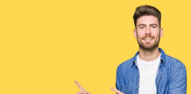 Gülümseyen ve iki elleri ve parmakları ile tarafına işaret kamera bakarak rahat denim ceket giyen genç yakışıklı sarışın adam.