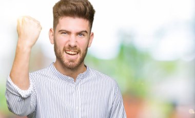 Öfkeyle bağırırken sinirli ve öfkeli genç ve yakışıklı bir adam yumruk kaldırıyor. Öfke ve agresif kavram.