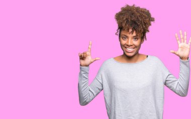 Güzel genç Afro-Amerikan kadın gösterilen ve parmakları ile işaret izole arka plan yüzünden kendinden emin ve mutlu gülümseyerek süre yedi numara.