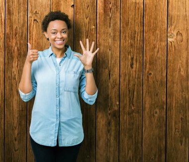 Gösterilen ve parmakları ile işaret izole arka plan üzerinde genç güzel bir Afrikalı-Amerikalı kadın kendinden emin ve mutlu gülümseyerek süre 6 numara.