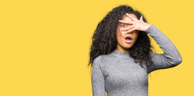 Küçük güzel kız kıvırcık saç şok kapsayan yüz ve gözleri el ile göz, utanmış ifade ile parmaklar bakarak.