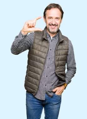Orta Çağ yakışıklı adam kış yelek giyen gülümseyen ve emin el ile boyut işareti yaparken parmaklar ile görünümlü ve kamera bakıyor. Ölçü kavramı.