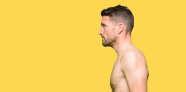 Çıplak göğüs tarafına, seyir gösteren yakışıklı gömleksiz adam sakin ol kendine güvenen gülümseme ile doğal yüz pozuyla profili.