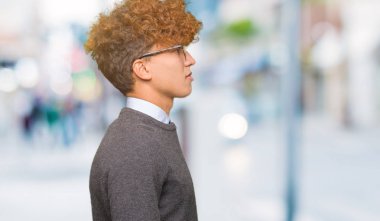 Afro saç ile genç yakışıklı iş adamı yan arayan gözlük giyen, güvenli bir gülümseme ile doğal yüzü ile profil poz rahatlayın.