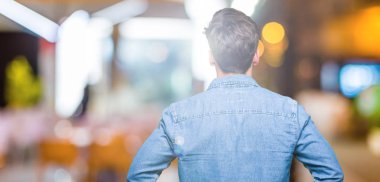 Yakışıklı delikanlı izole arka plan ayakta geriye doğru uzakta silah ile vücut üzerinde seyir üzerinde güneş gözlüğü takıyor