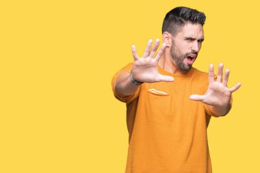 Genç yakışıklı adam şokta bağırarak korkuyor ve dehşet korku ifade dur hareketi el ile ile izole arka plan üzerinde. Panik kavramı.