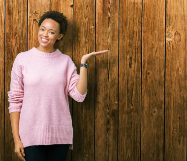 Neşeli sunulması ve kameraya bakarak avucunun ile işaret gülümseyen izole arka plan güzel genç Afro-Amerikan kadın.