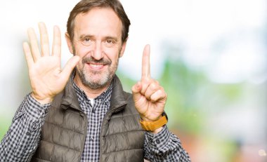 Kış yelek gösterme ve parmakları ile işaret giyen orta yaş yakışıklı adam kendinden emin ve mutlu gülümseyerek süre 6 numara.