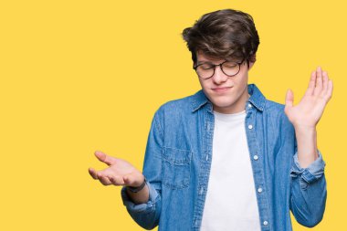 İzole arka plan clueless ve şaşkın bir ifadeyle kollar ve eller kaldırdı üzerinde gözlük takan yakışıklı delikanlı. Şüphe kavramı.