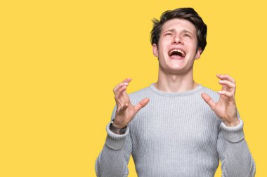 Üzerinde kış kazak giyen genç yakışıklı adam arka plan deli izole ve deli bağırarak ve agresif ifade ve silah kaldırdı bağırıyor. Hayal kırıklığı kavramı.