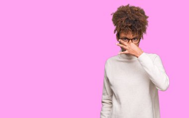 Gözlük takan bir şey pis ve iğrenç kokulu izole arka plan, dayanılmaz koku, holding nefes burun parmaklar ile güzel genç Afro-Amerikan kadın. Kötü kokuyor kavramı.