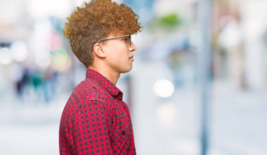 Tarafına, seyir güneş gözlüğü takıyor afro saçlı Genç yakışıklı adam sakin ol kendine güvenen gülümseme ile doğal yüz pozuyla profili.