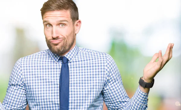 Handsome business man wearing tie clueless and confused expression with arms and hands raised. Doubt concept.