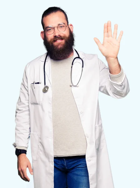 年轻的金发医生男子与胡子穿着医疗外套豁免说你好快乐和微笑 友好的欢迎手势 — 图库照片