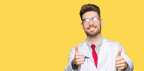 年轻英俊的科学家男子戴眼镜 赞同用手做积极的手势 竖起大拇指微笑 为成功而高兴 看着镜头 赢家的手势 — 图库照片