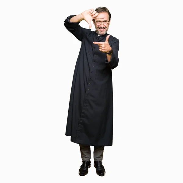 幸せそうな顔で手と指でフレームを作るカトリックのローブを着た中年の司祭の男 創造性と写真のコンセプト — ストック写真