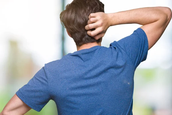 İzole arka plan geriye düşünme hakkında şüphe ile baş taraftan üzerinde mavi t-shirt giyen genç yakışıklı adam