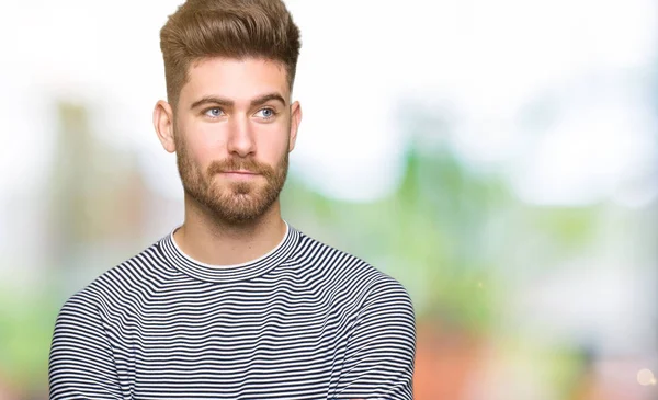 Genç yakışıklı adam giyen çizgili süveter gülümseyen görünümlü yan ve dik dik bakma uzağa düşünce.
