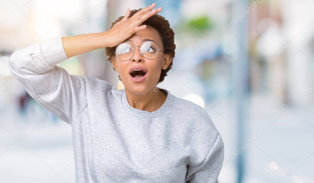 Young beautiful african american woman wearing glasses over isolated background surprised with hand on head for mistake, remember error. Forgot, bad memory concept.