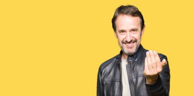 Orta yaş yakışıklı adam beckoning gel burada mutlu ve gülümseyerek el davet ile jest siyah deri ceket